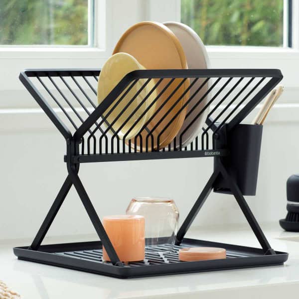 התקן ייבוש כלים מתקפל קטן שחור Brabantia מוסיף סטיילינג לדלפק המטבח שלך, מחזיק צלחות, כוסות וכלים. ליד החלון עם נוף ירוק, הוא מביא קסם של כלי בית לדלפקים ומסגרות לבנים פריכים. - vavaVoom.co.il