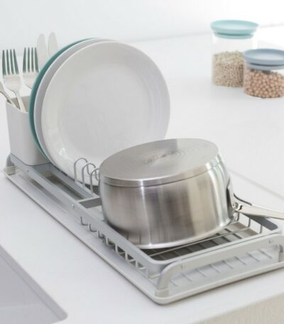 התקן ייבוש כלים קטן אפור Brabantia על השיש מחזיק סיר, שתי צלחות וסכו"ם, כשברקע שני צנצנות עם קטניות מוסיפות לקטע דקור נקי וסטיילינג מינימליסטי לכלי בית. - vavaVoom.co.il