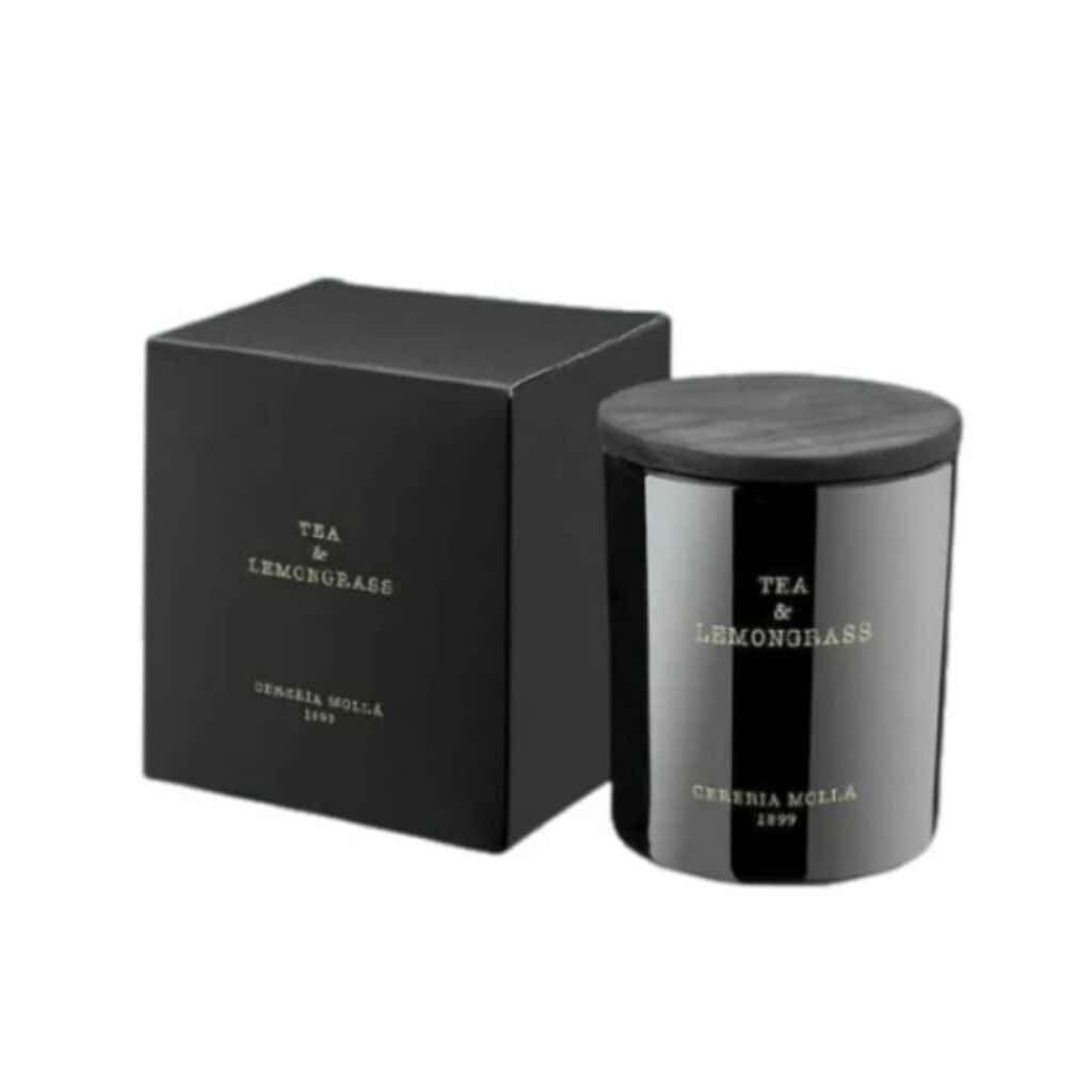 נר בצנצנת שחורה עם הכיתוב "TEA&LEMONGRASS - גר׳ 230" מונח לצד קופסה תואמת, שניהם עם הלוגו האלגנטי של CERERIA MOLLÁ 1899 בזהב. - vavaVoom.co.il
